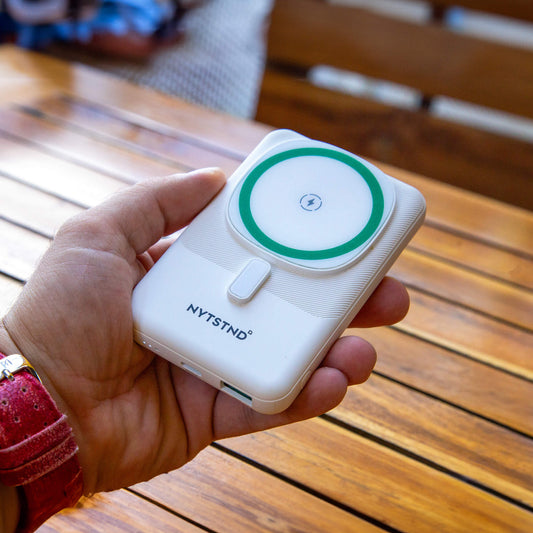 A white NYTSTND Pulse Power Bank with a green circle indicating the magnetic charging area, featuring an adjustable kickstand.