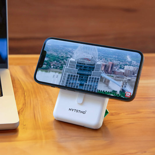 A white NYTSTND Pulse Power Bank with a green circle indicating the magnetic charging area, featuring an adjustable kickstand.