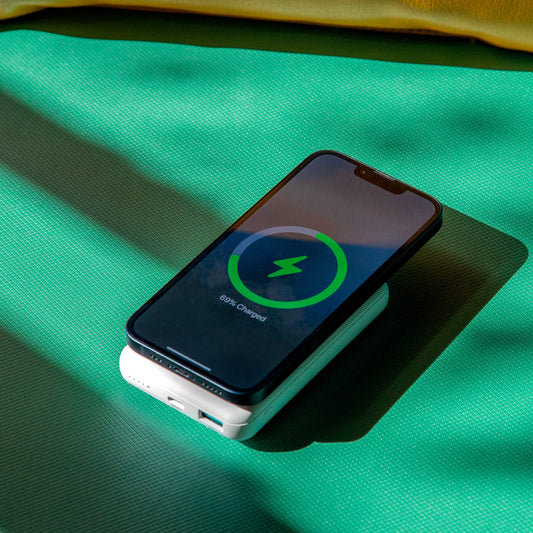 A white NYTSTND Pulse Power Bank with a green circle indicating the magnetic charging area, featuring an adjustable kickstand.