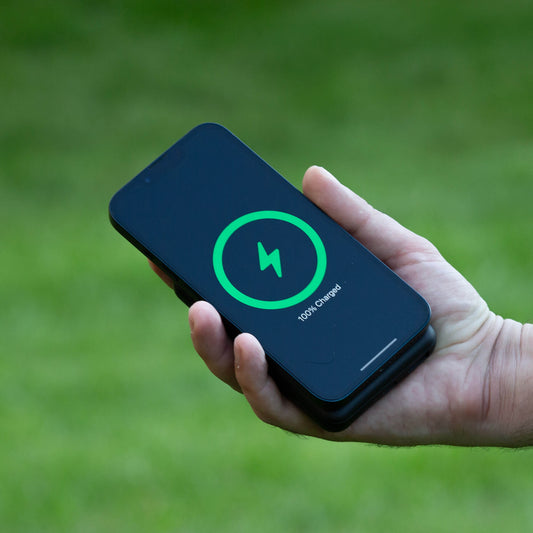 A black NYTSTND Pulse Power Bank with a green accent on the magnetic charging surface, standing upright with an adjustable kickstand.