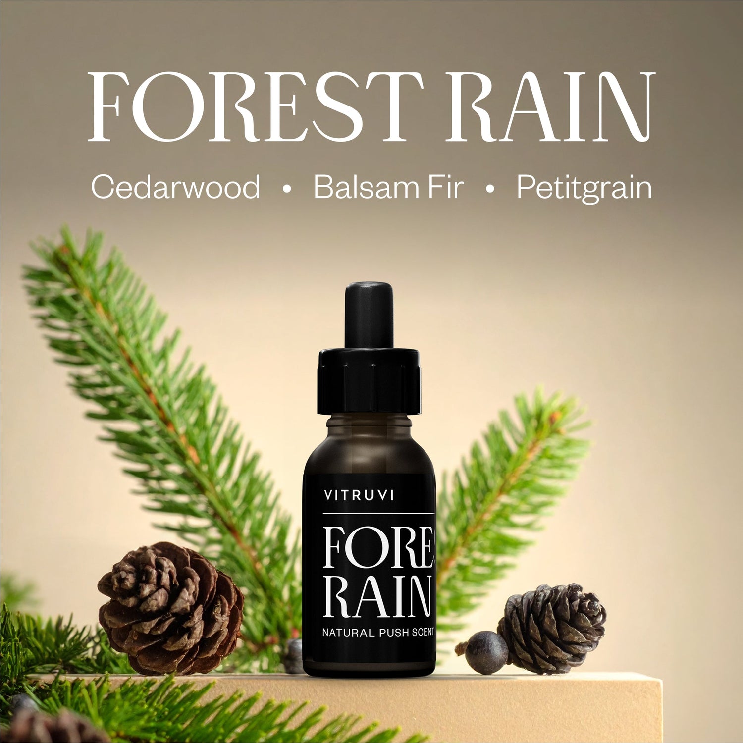 Vitruvi Forest Rain essential oil bottle with pine branches and cones on a beige background