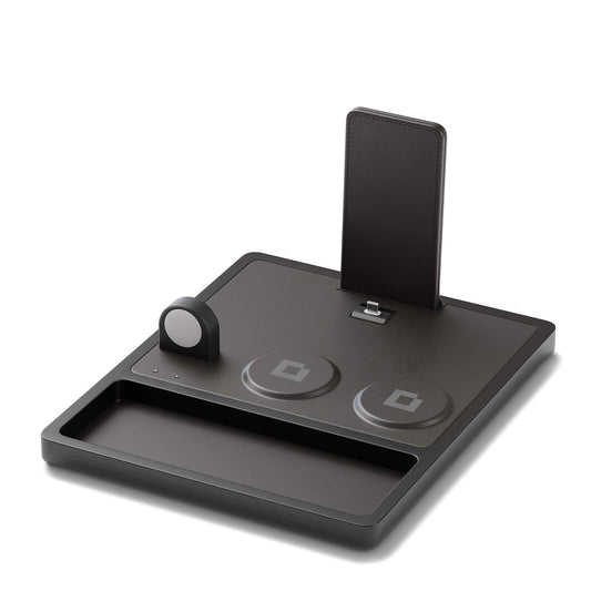 A black 4-in-1 MagSafe wireless charging station with separate sections for charging an iPad, Apple Watch, and other devices, displaying LED indicators.