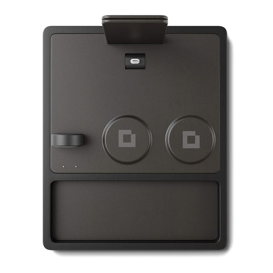A black 4-in-1 MagSafe wireless charging station with separate sections for charging an iPad, Apple Watch, and other devices, displaying LED indicators.
