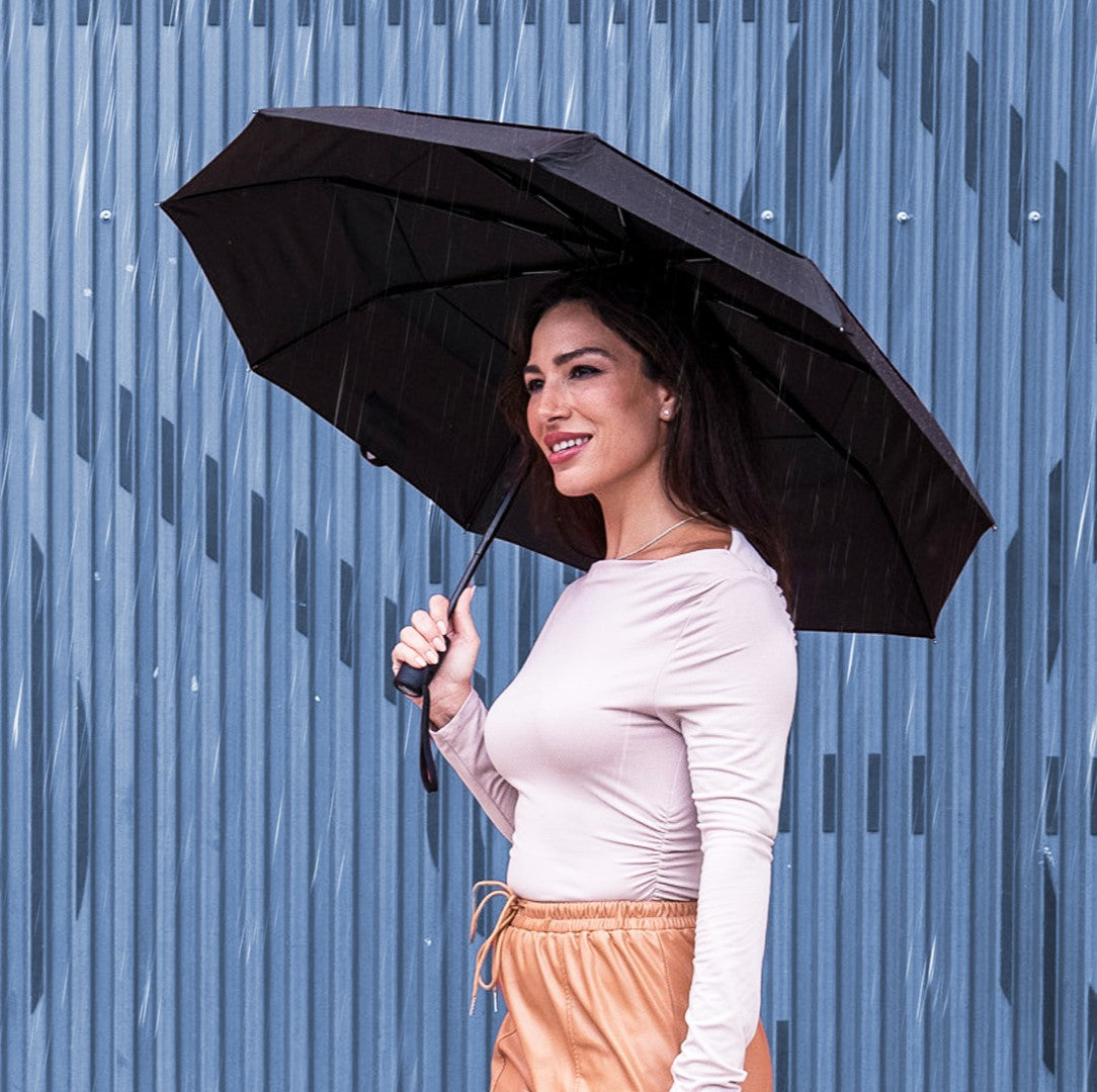Woman holding a black umbrella against a blue raindrop background