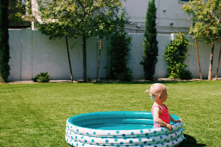 Child playing in a polka dot inflatable pool in a backyard