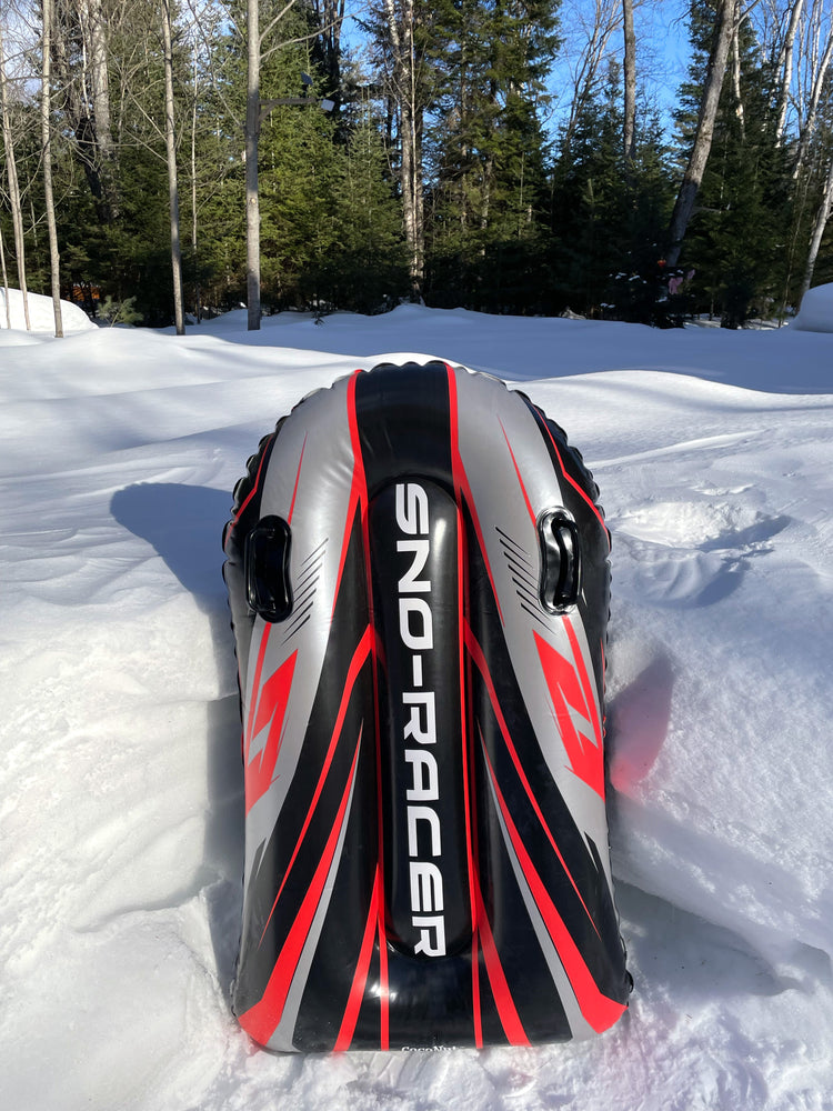 Inflatable sled labeled 'Sno-Racer' on a snowy ground with trees in the background