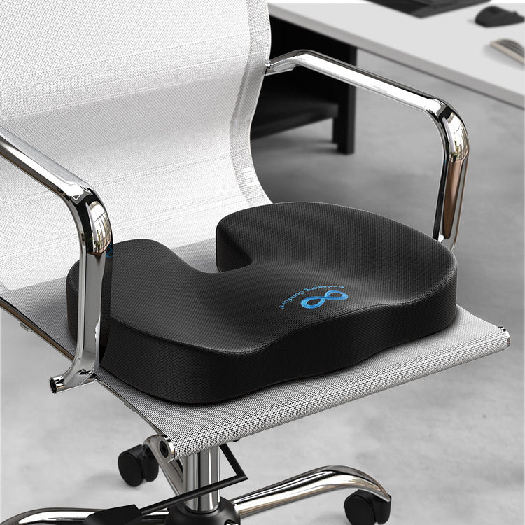 Black ergonomic seat cushion on a office chair with a desk in the background