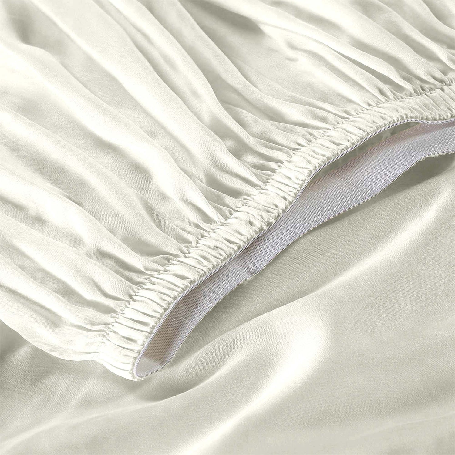 Close-up of a fitted sheet on a bed with a plain background