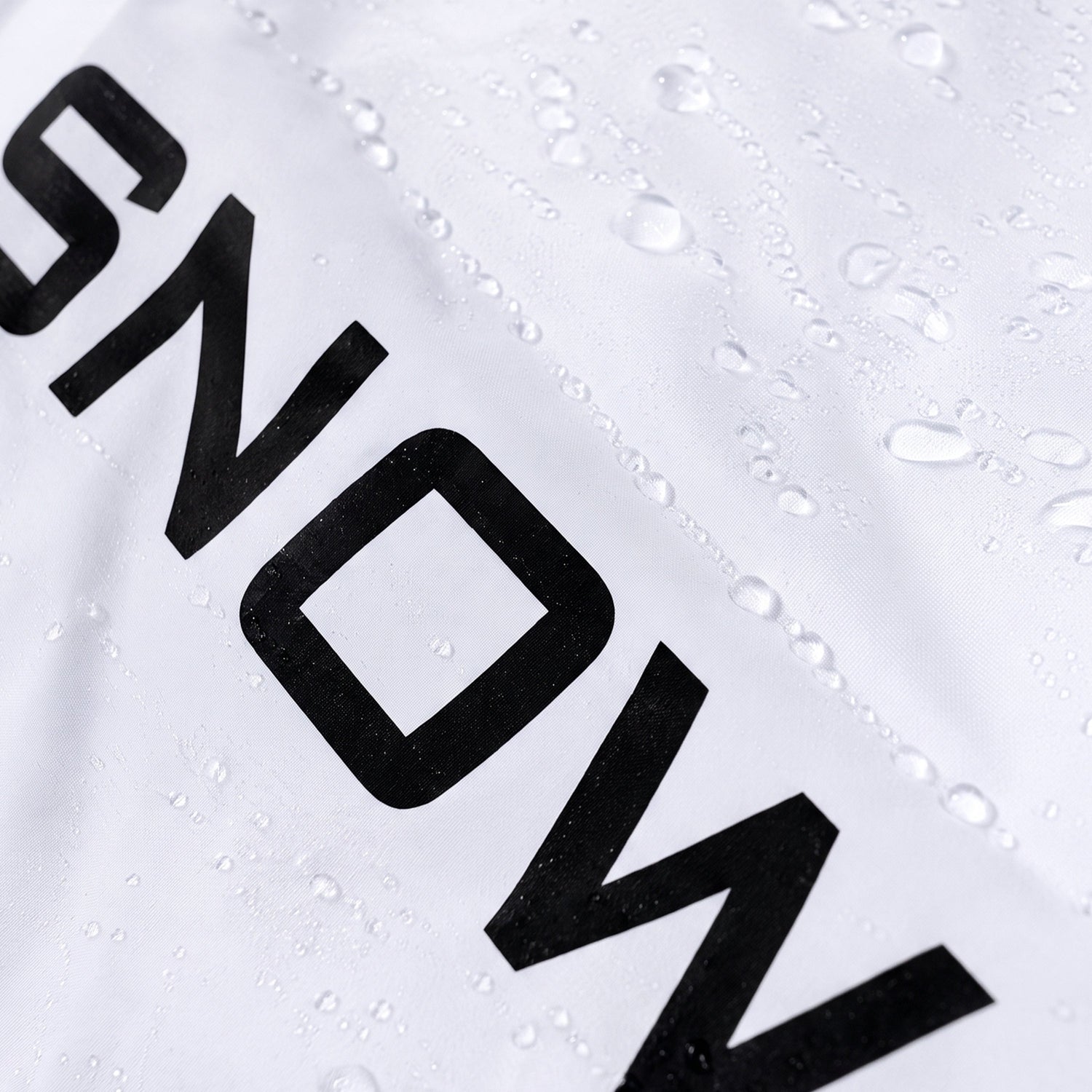 Close-up of a white athletic garment with bold black lettering and water droplets on the surface.