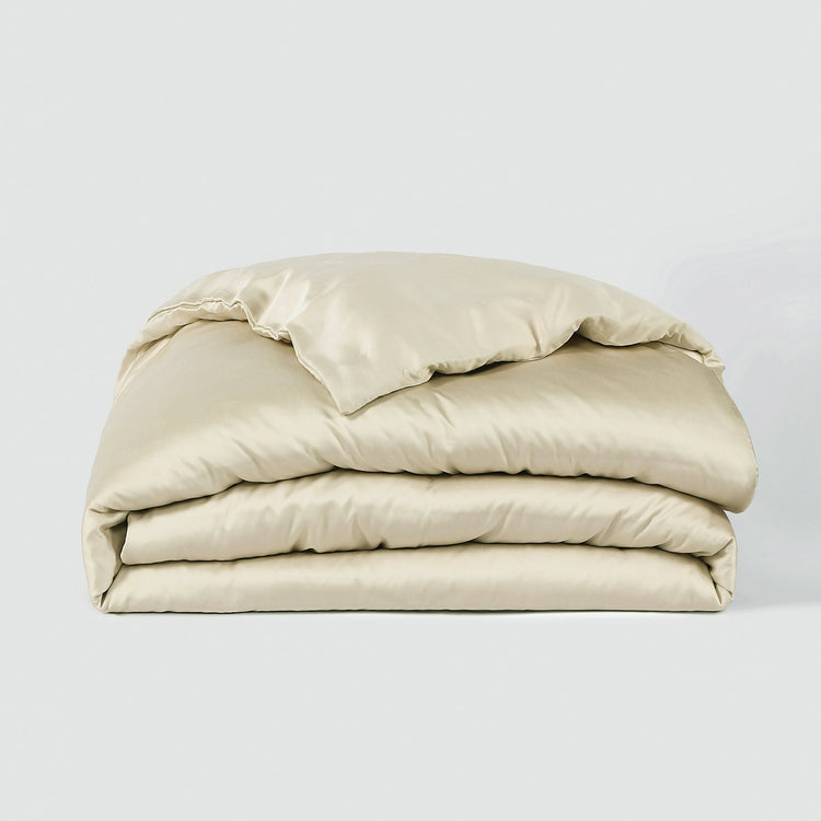 Stack of beige comforters on a light gray background