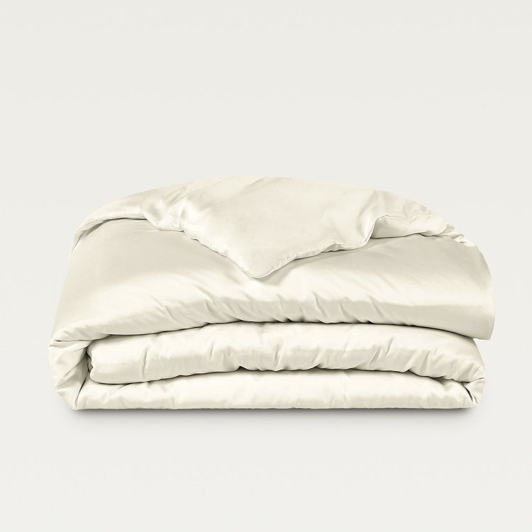Folded beige comforter on a light gray background