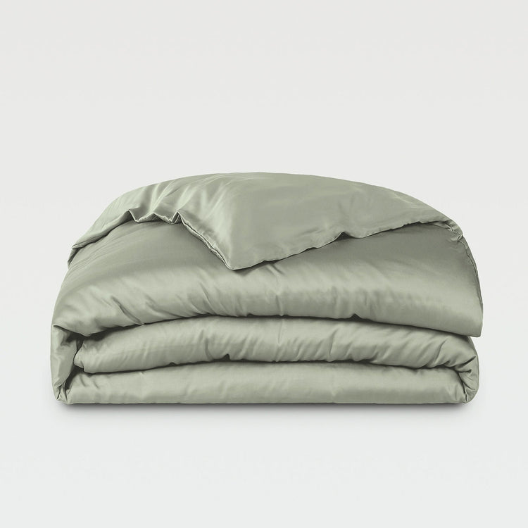 Folded green comforter on a white background