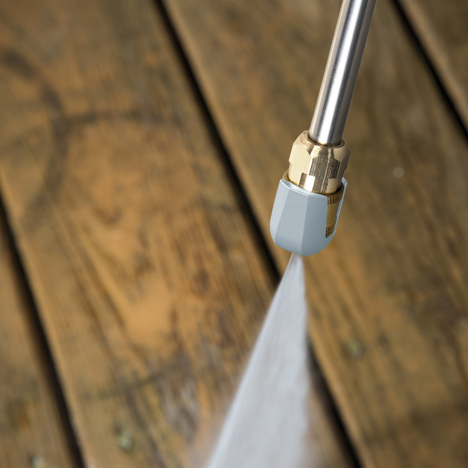 Pressure washer nozzle spraying water on a wooden surface