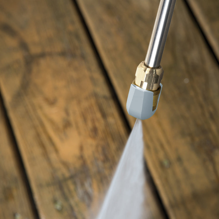 Pressure washer nozzle spraying water on a wooden surface