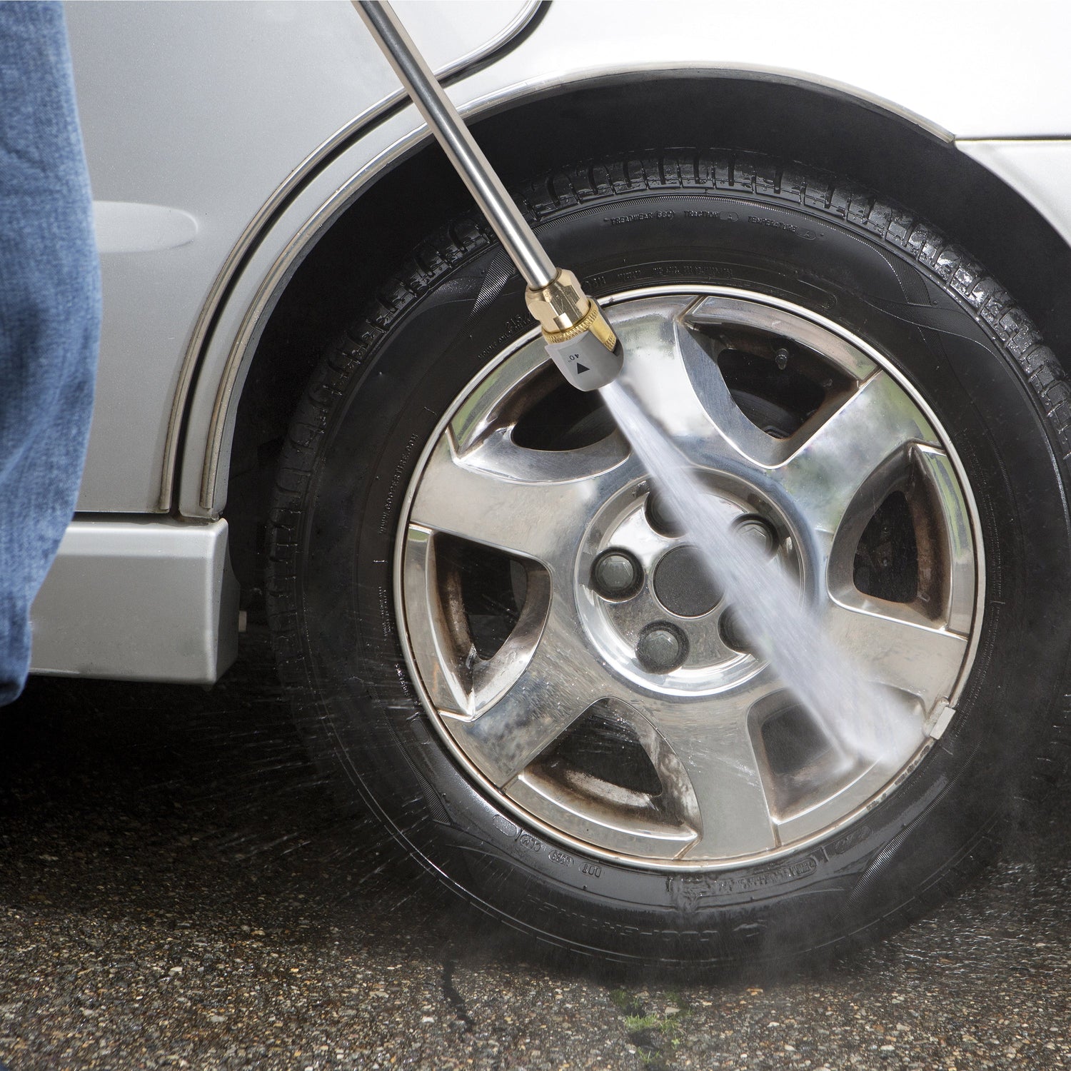 Person using a pressure washer to clean a car tire