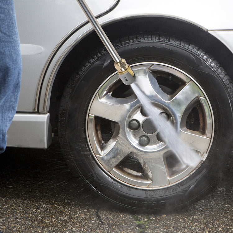 Person using a pressure washer to clean a car tire