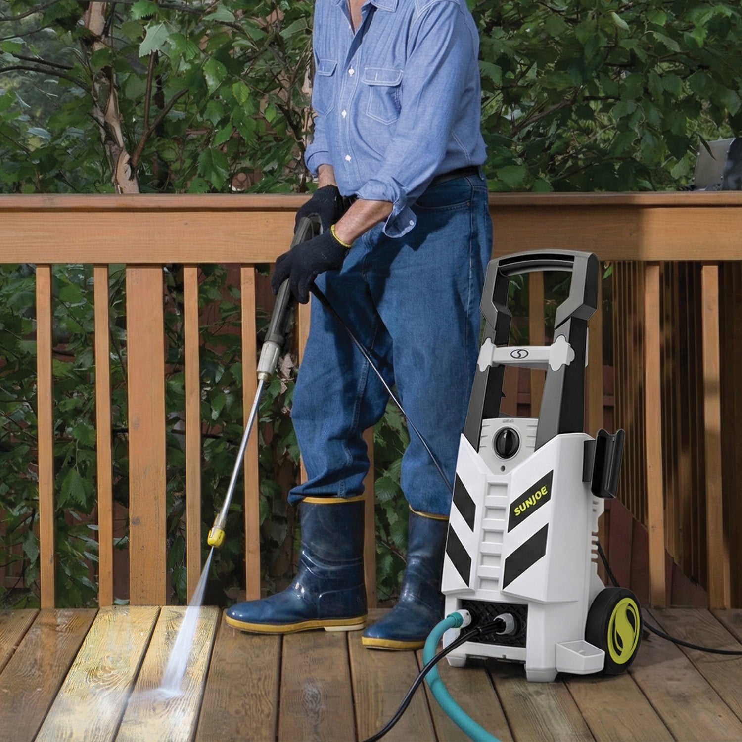 Person using a pressure washer on a wooden deck