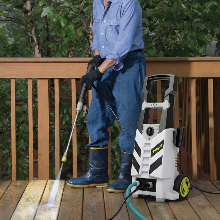 Person using a pressure washer on a wooden deck