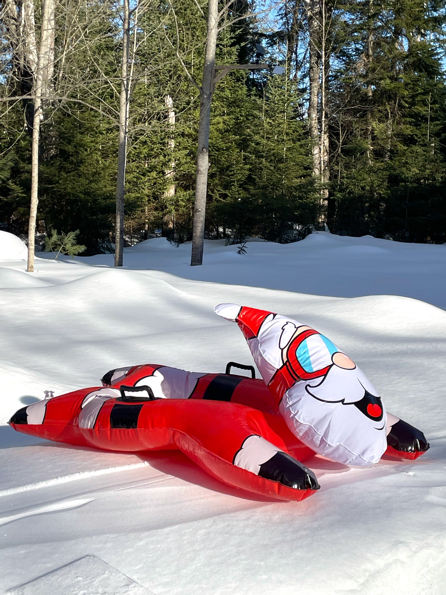 Inflatable Santa Claus snow tube on a snowy landscape with trees in the background