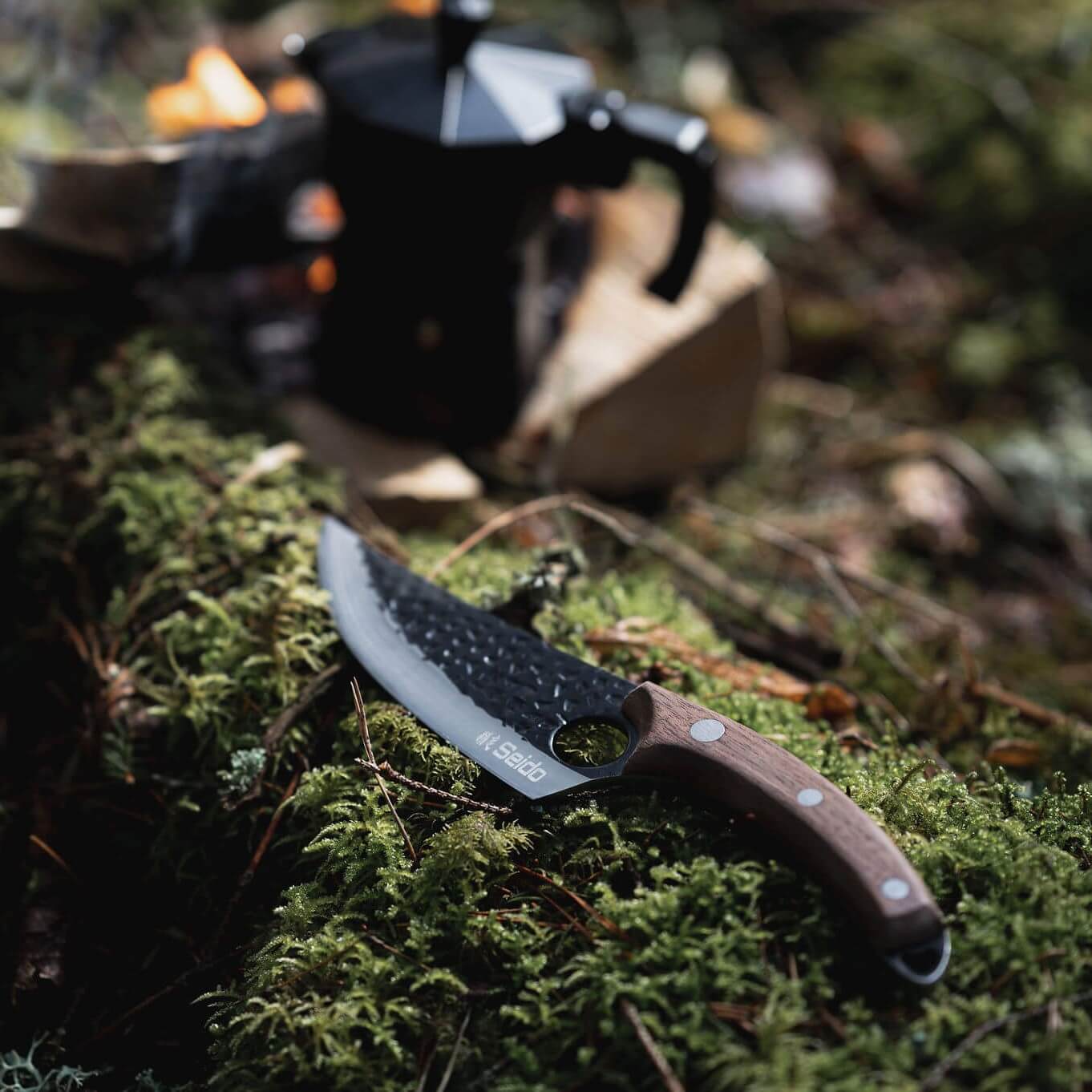 Knife with a brown handle on green moss in a forest setting