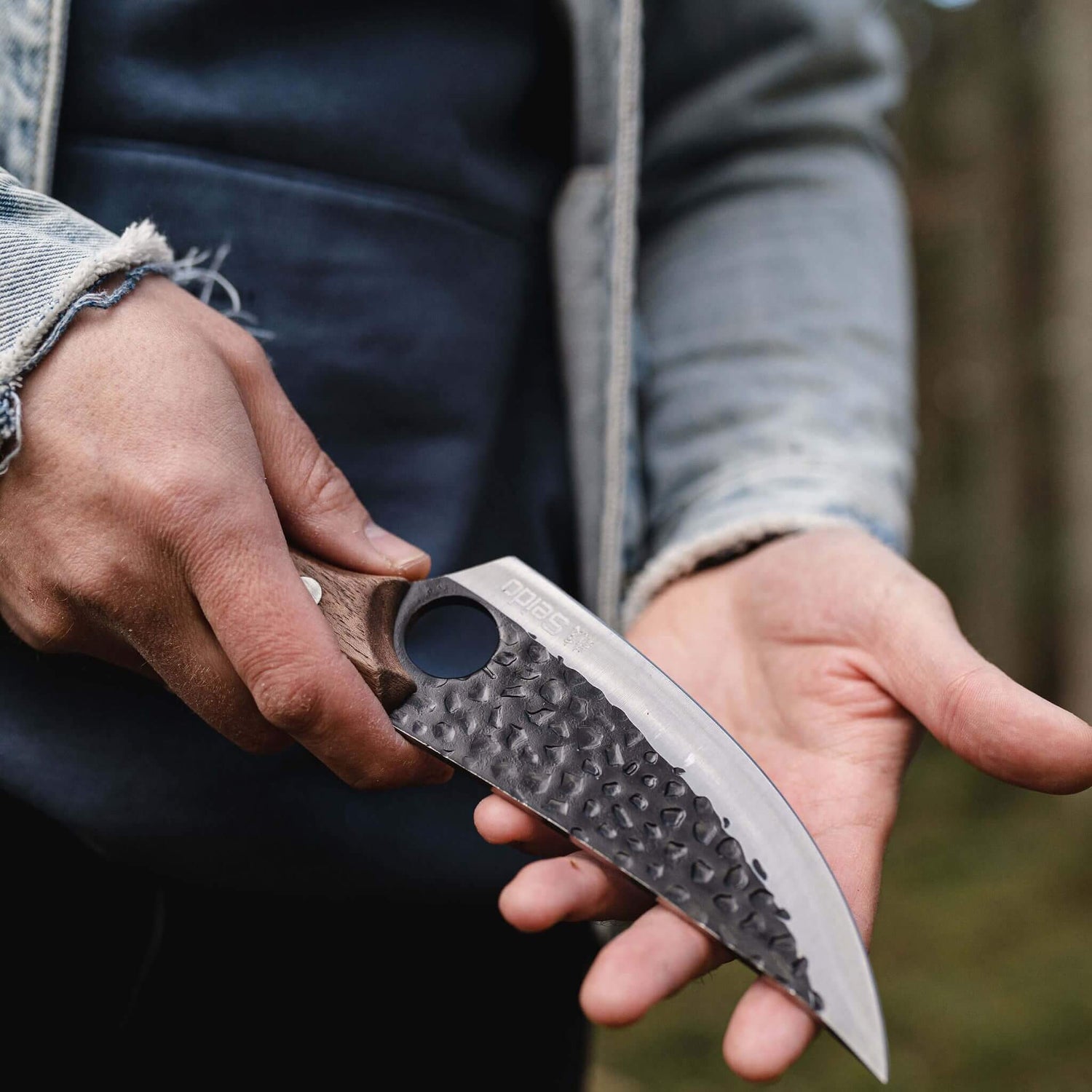 Person holding a knife with a textured handle and blade