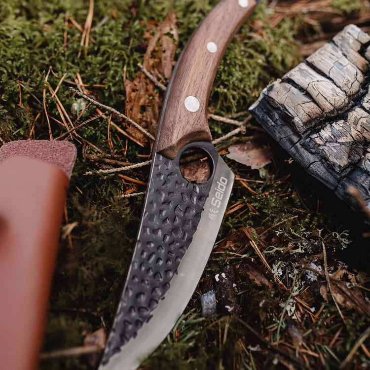Folding knife with wooden handle on a mossy ground