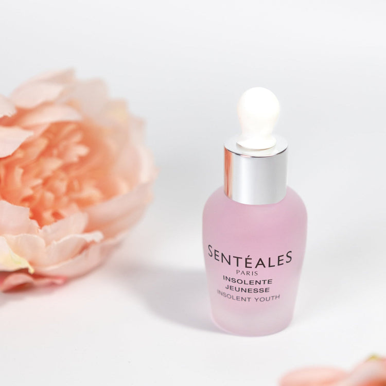 Pink skincare serum bottle with floral background