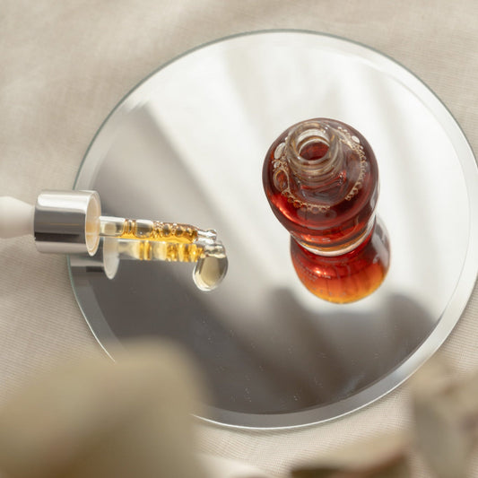 Hand holding a Senteless skincare serum bottle with dropper against a neutral background