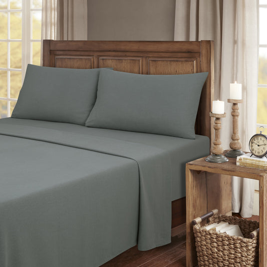 Gray bed sheets on a wooden bed with a wooden nightstand and decor items.