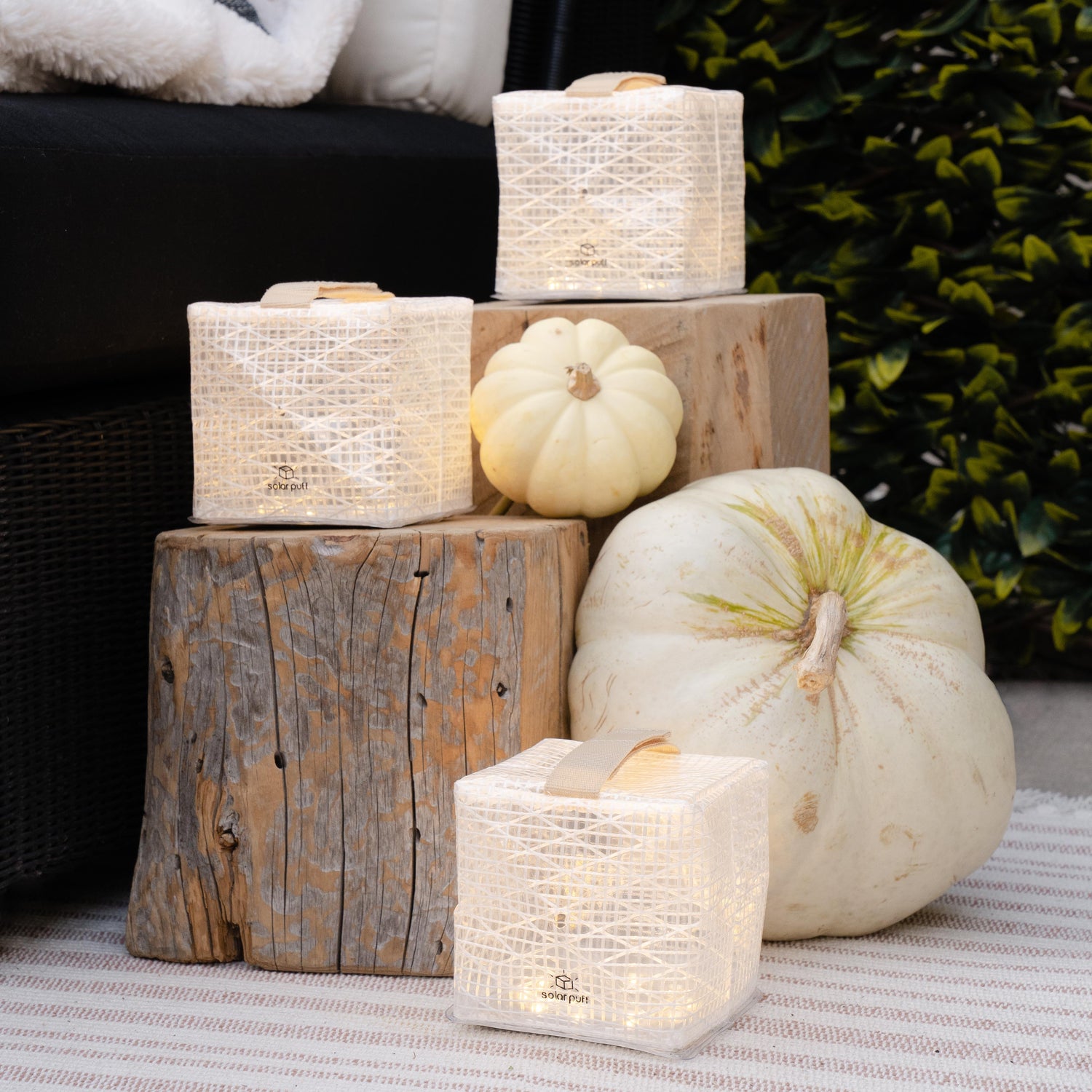 Decorative arrangement with candles and pumpkins on wooden blocks outdoors.
