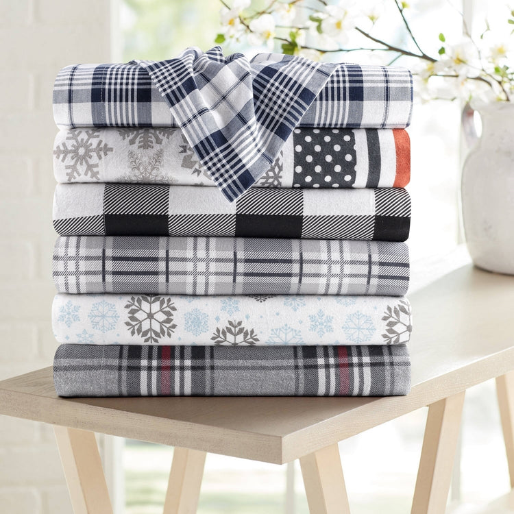 Stack of patterned blankets on a wooden table with a blurred background