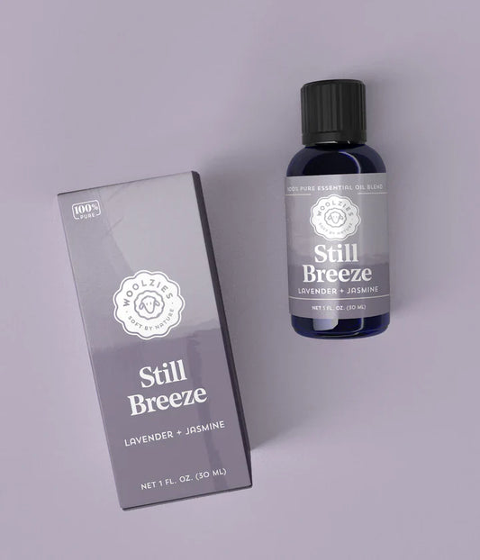 Bottle and box of 'Still Breeze' lavender and jasmine product on a light gray background