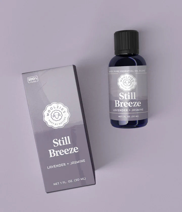 Bottle and box of 'Still Breeze' lavender and jasmine product on a light gray background