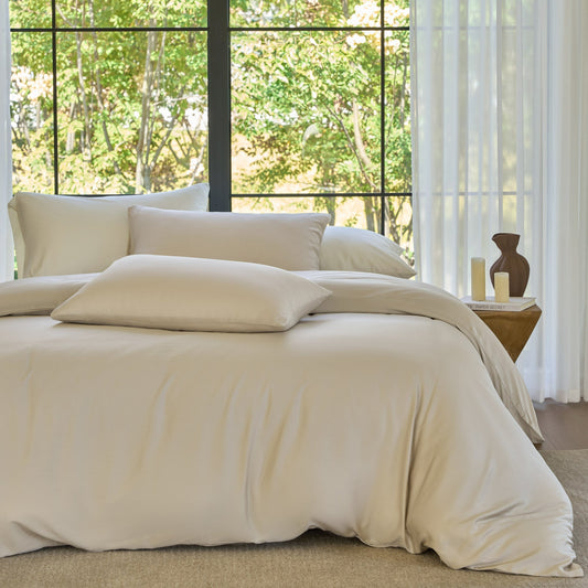 Beige bedding set on a bed with a window view of greenery