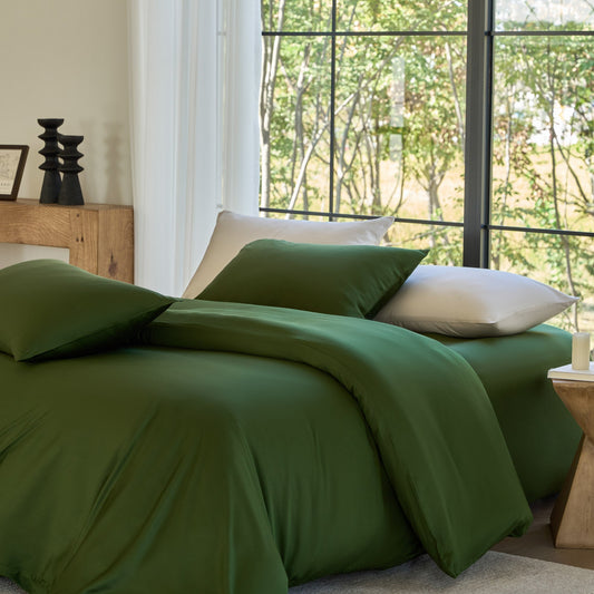 Green bedding set on a bed with a window view of trees