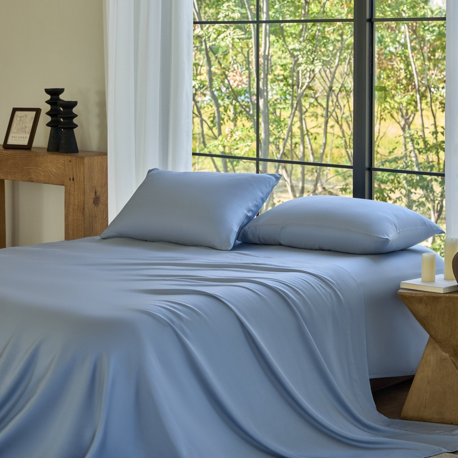 Blue bedding set on a bed with a window view of trees