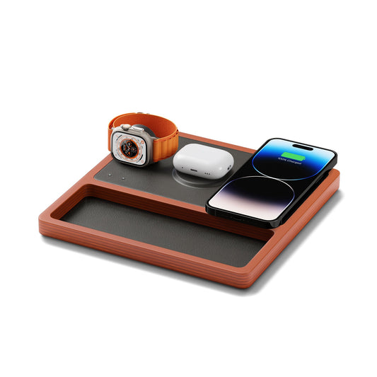 A wireless charging pad with integrated Apple Watch charger, featuring a black and oak design, with a smartphone, smartwatch, and earbuds being charged.