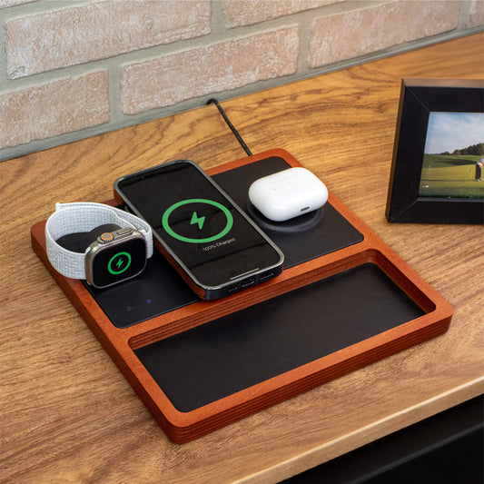 A wireless charging pad with integrated Apple Watch charger, featuring a black and oak design, with a smartphone, smartwatch, and earbuds being charged.