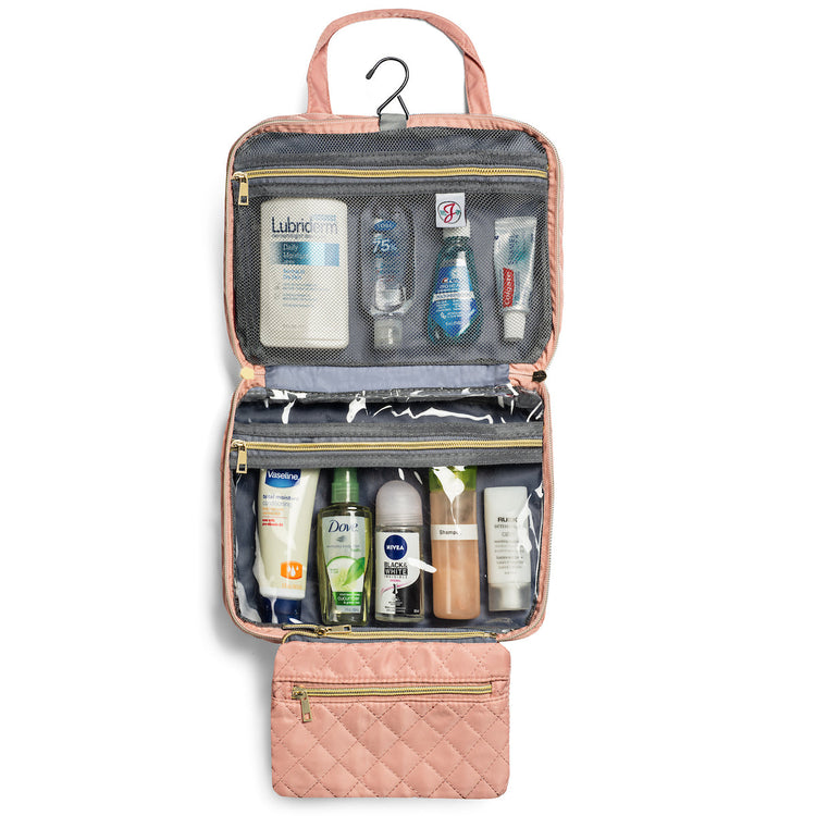 Pink toiletry bag with various skincare products on a white background