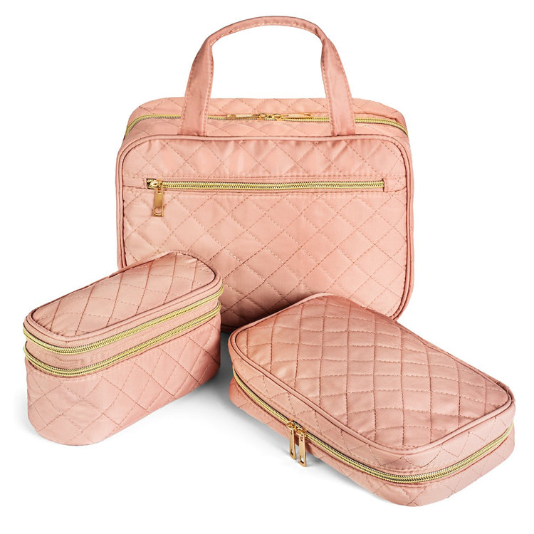 Set of three pink quilted travel bags with gold zippers on a white background