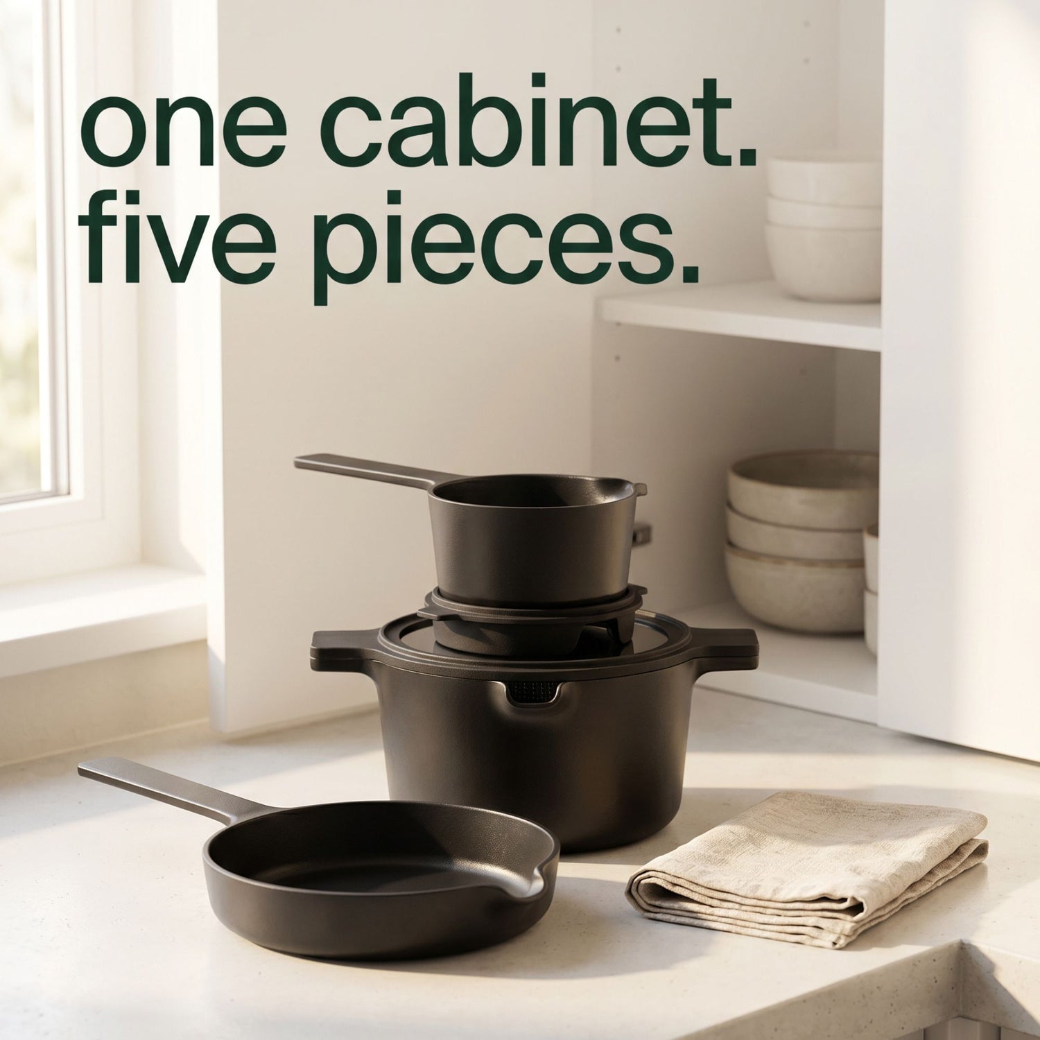 Black cookware set on a kitchen counter with text 'one cabinet. five pieces.'