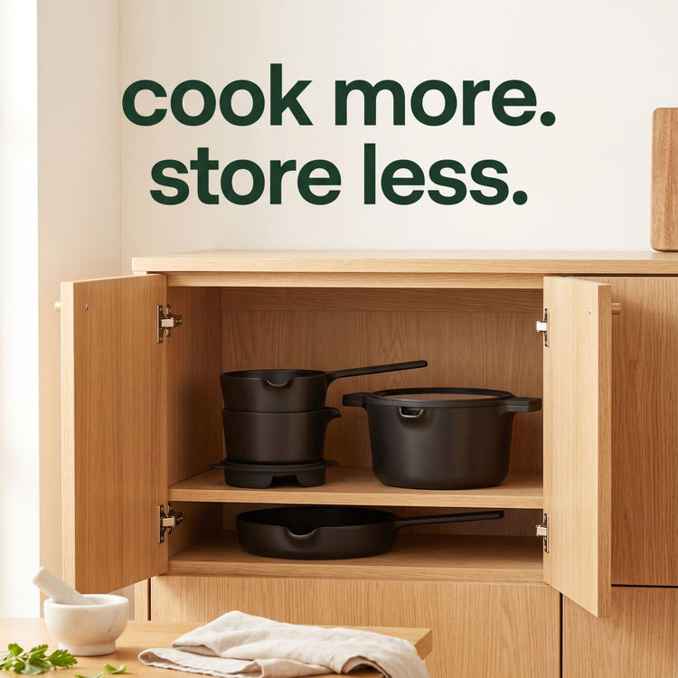 Wooden cabinet with black cookware inside, featuring the text 'cook more. store less.'