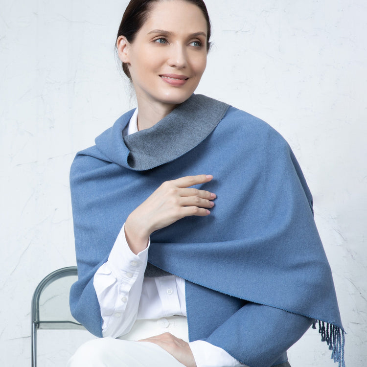 Woman wearing a blue shawl over a white outfit against a light gray background