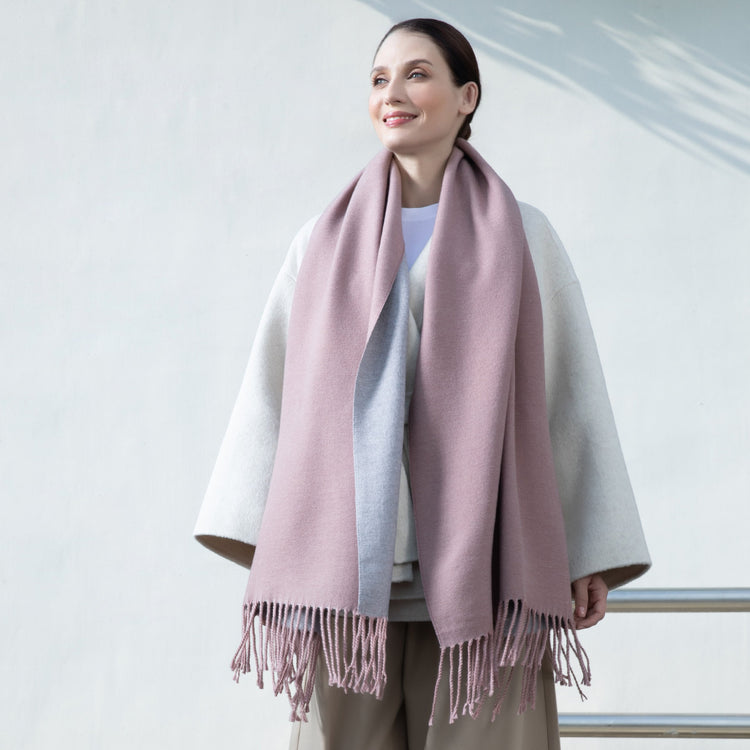 Woman wearing a pink scarf with a white and gray outfit against a light background