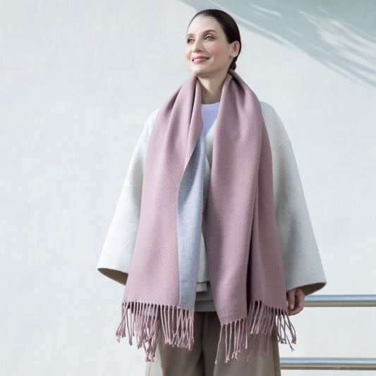 Woman wearing a pink scarf with a white and gray outfit against a light background