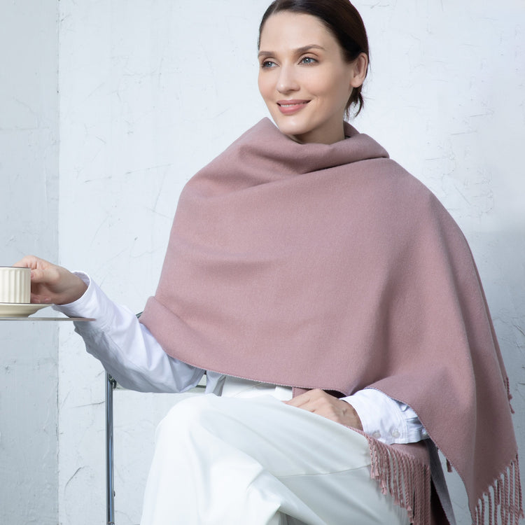 Woman wearing a pink shawl holding a cup against a white background