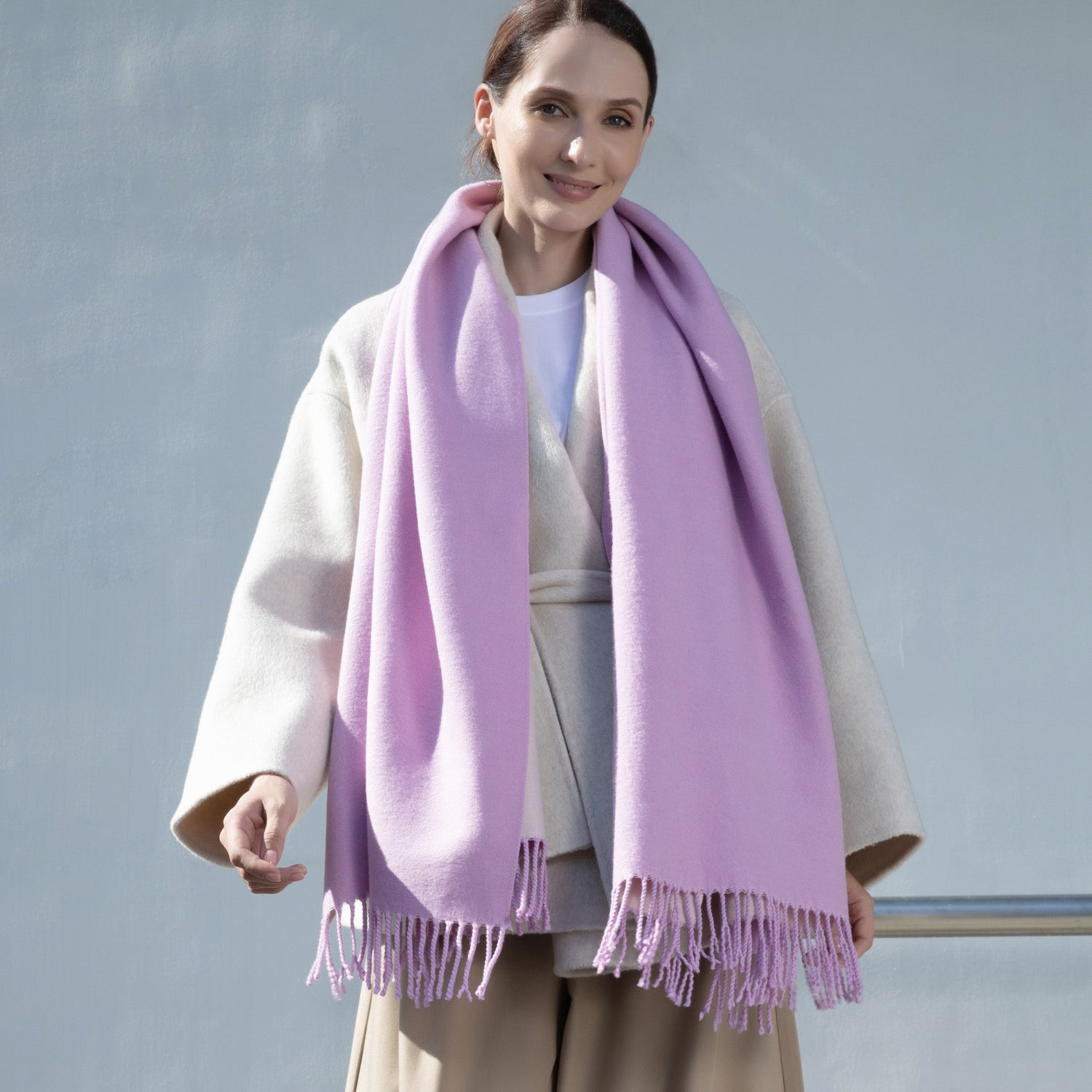 Woman wearing a light purple scarf with a plain background