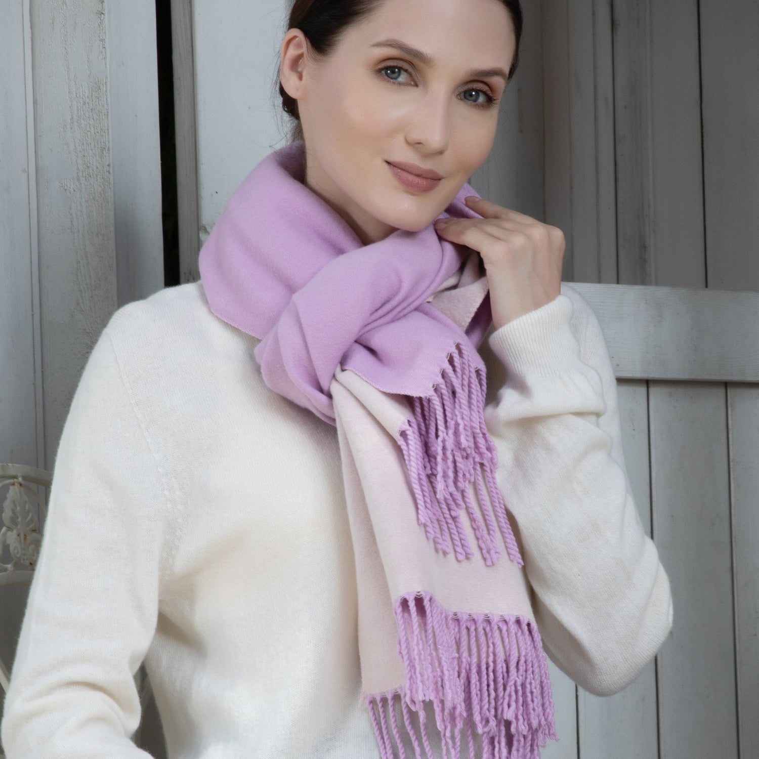 Woman wearing a purple scarf and white sweater against a wooden background