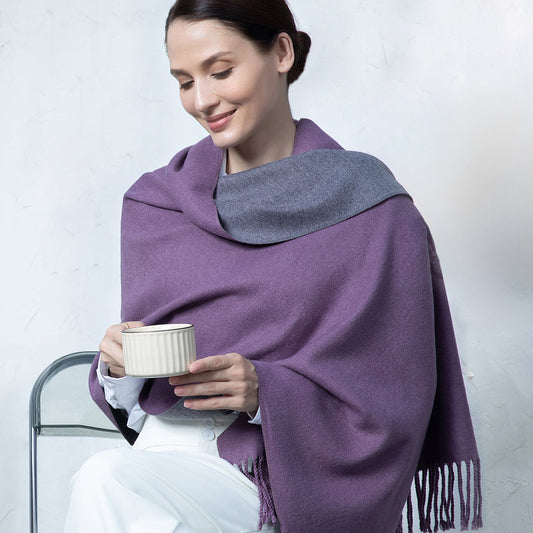 Woman wearing a purple and gray shawl holding a cup against a white background