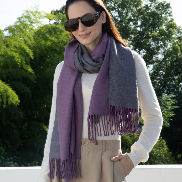 Woman wearing a purple and gray scarf outdoors with green trees in the background